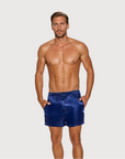 Man wearing the Luné d’Or Men’s Satin Lounge Short in navy, front view showing the elastic waistband and side pockets.