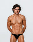 Man wearing the Luné d’Or Éclat Men’s Jockstrap in metallic black, front view showing the high-shine liquid-metallic finish and sculpted contour pouch.
