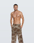 Man wearing the Luné d’Or Men’s Satin Lounge Pant in leopard print, front view showing the elastic waistband and wide straight leg.