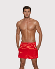 Man wearing the Luné d’Or Men’s Satin Lounge Short in red, front view showing the elastic waistband and side pockets.