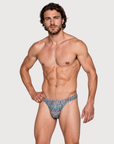 Man wearing the Luné d’Or Mirage Men’s Thong in iridescent leopard, front view showing the printed contour pouch.