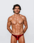 Man wearing the Luné d’Or Éclat Men’s Jockstrap in metallic red, front view showing the high-shine liquid-metallic finish and sculpted contour pouch.